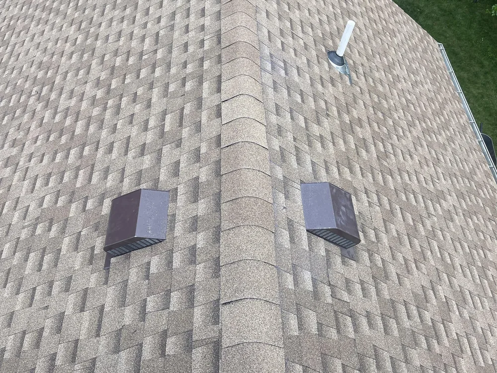 New tan architectural shingles with two box vents on a finished roof slope